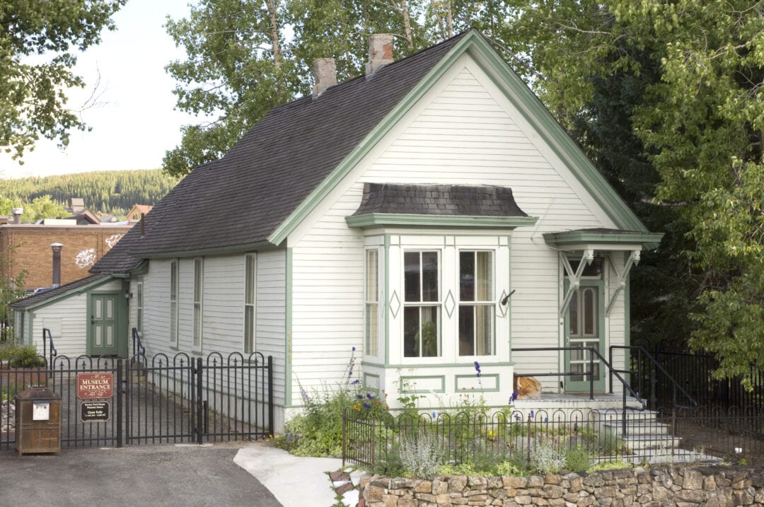 A small white house with a black roof and black awnings.