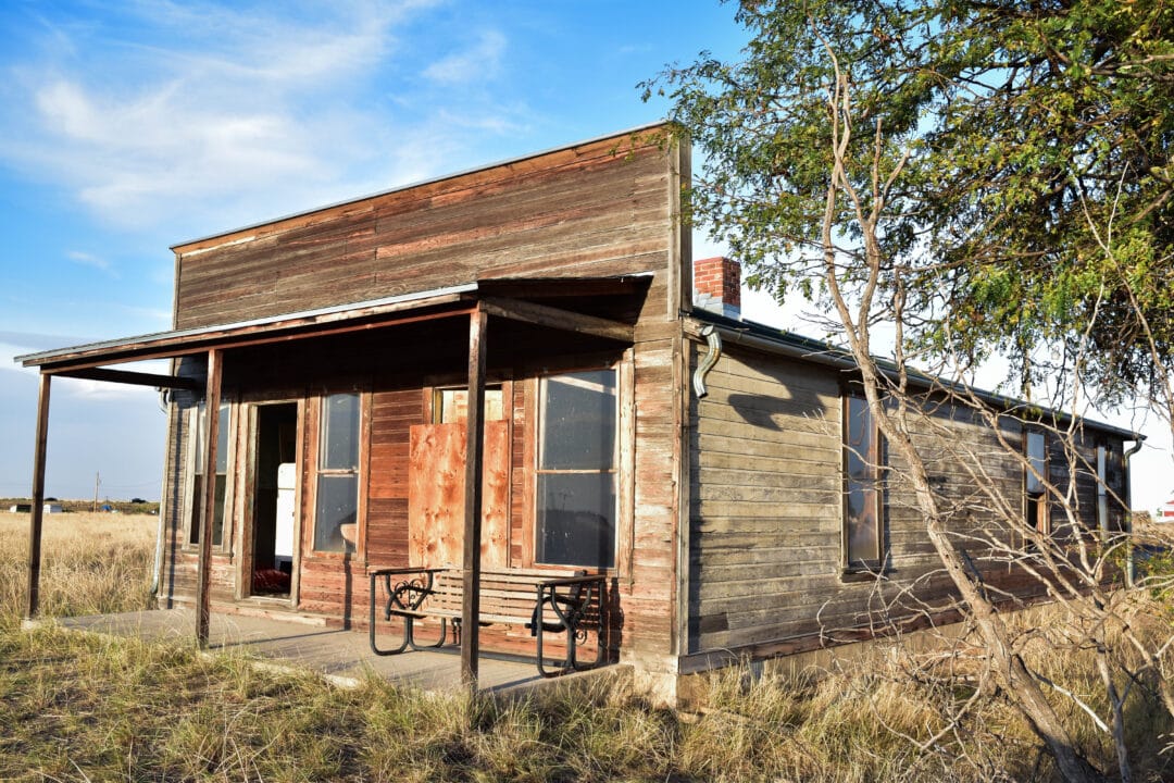 An abandoned wood building sits in a field.