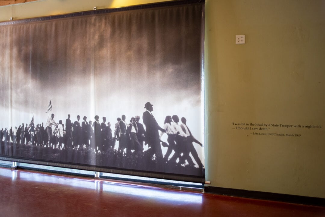 a black and white photo enlarged on a wall of civil rights marchers next to a quote by john lewis