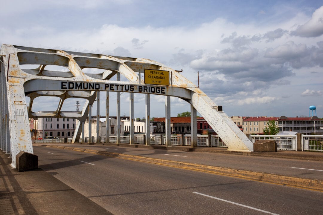 a steel arch bridge over a four lane road with selma in the background