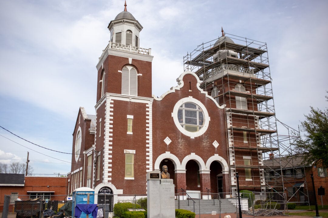 a red brick and white church with two towers, one of which is wrapped in scaffolding