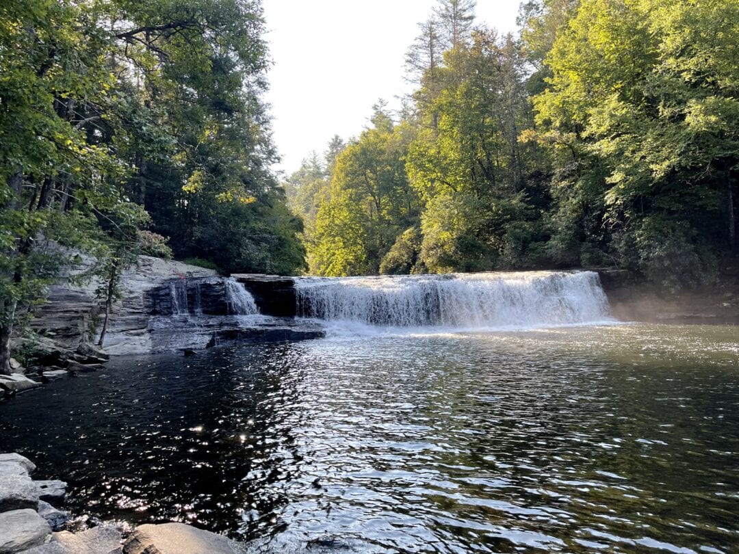 A long waterfall cascades into a waterway at DuPont State National Forest
