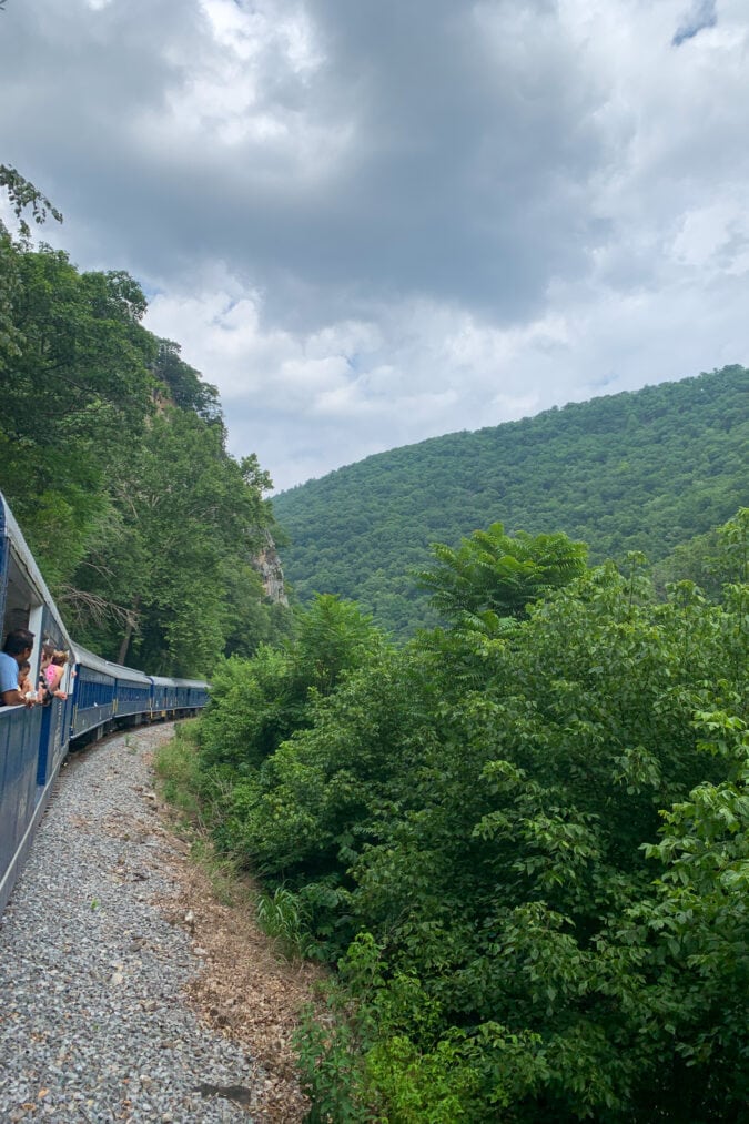 A train rounds a bend through a hilly terrain