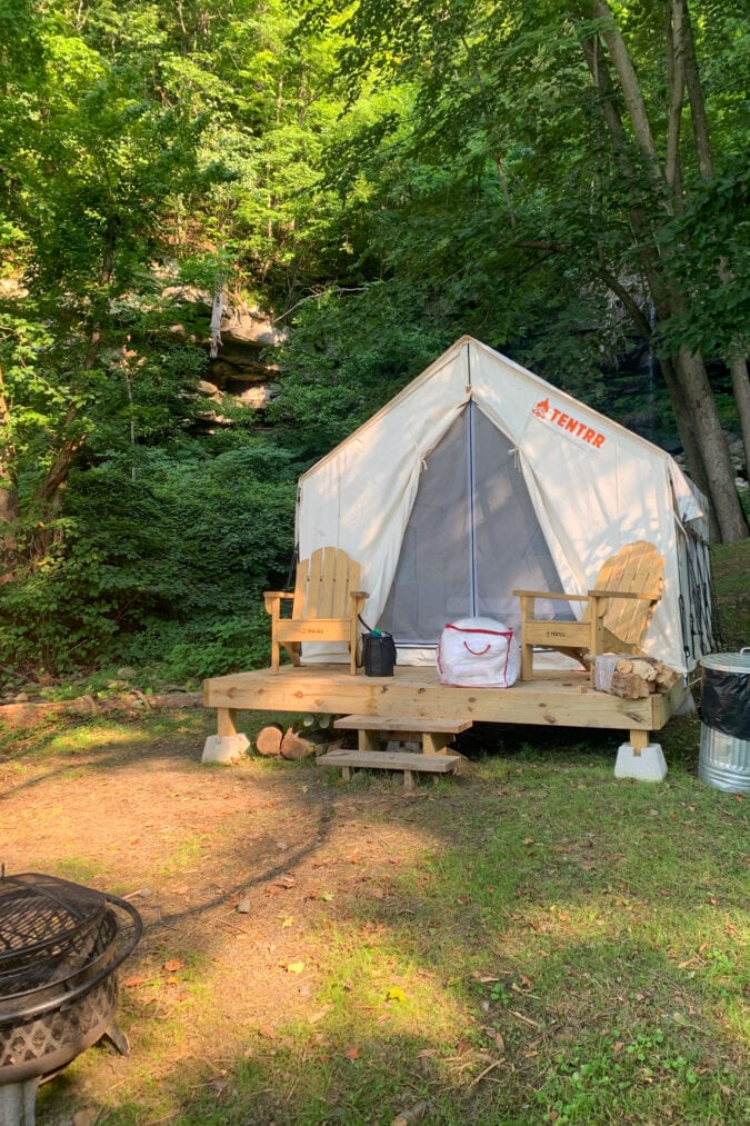 A tent features a wooden front porch area with two chairs