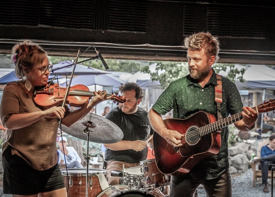 Band members play a guitar, violin, and drums
