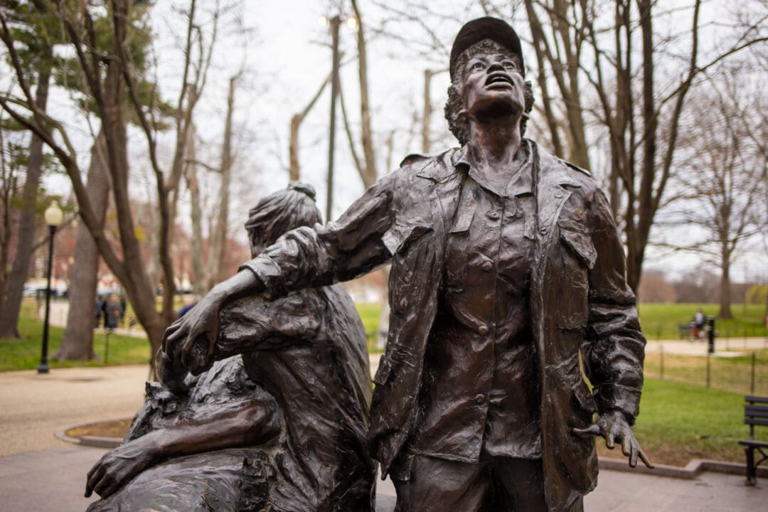 a bronze statue featuring two women nurses helping a fallen soldier