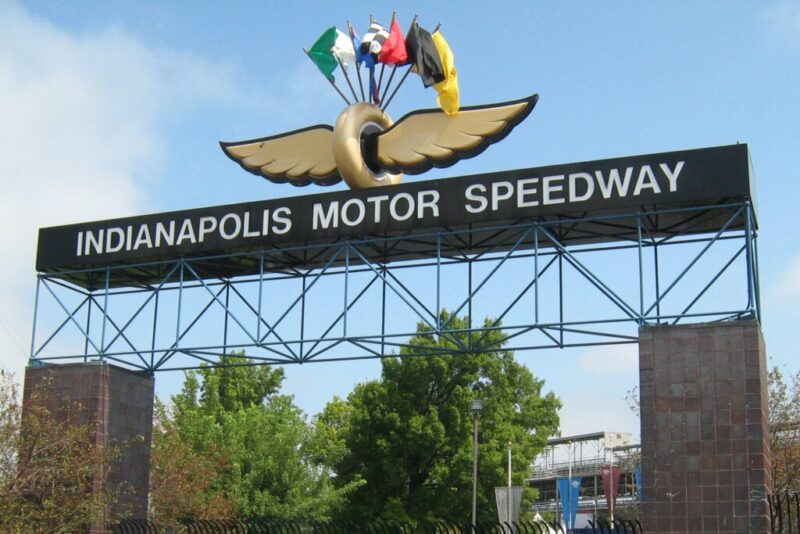 Signage outside of the Indianapolis Motor Speedway with acing flags sitting on top