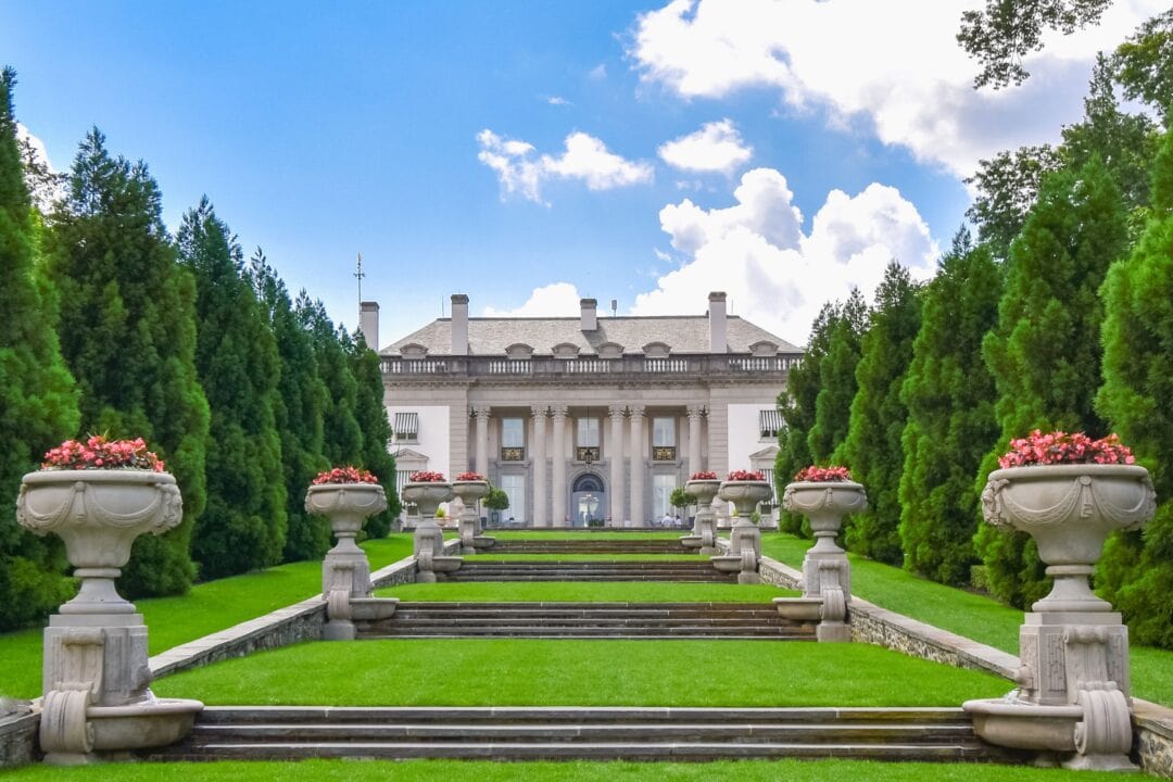 A stately manor sits atop a hill in the center of well-manicured lawns