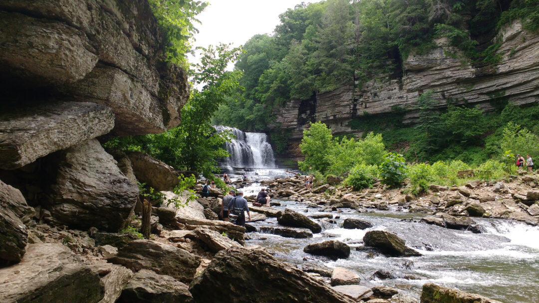 a rocky river with a waterfall in between two rocky cliffs