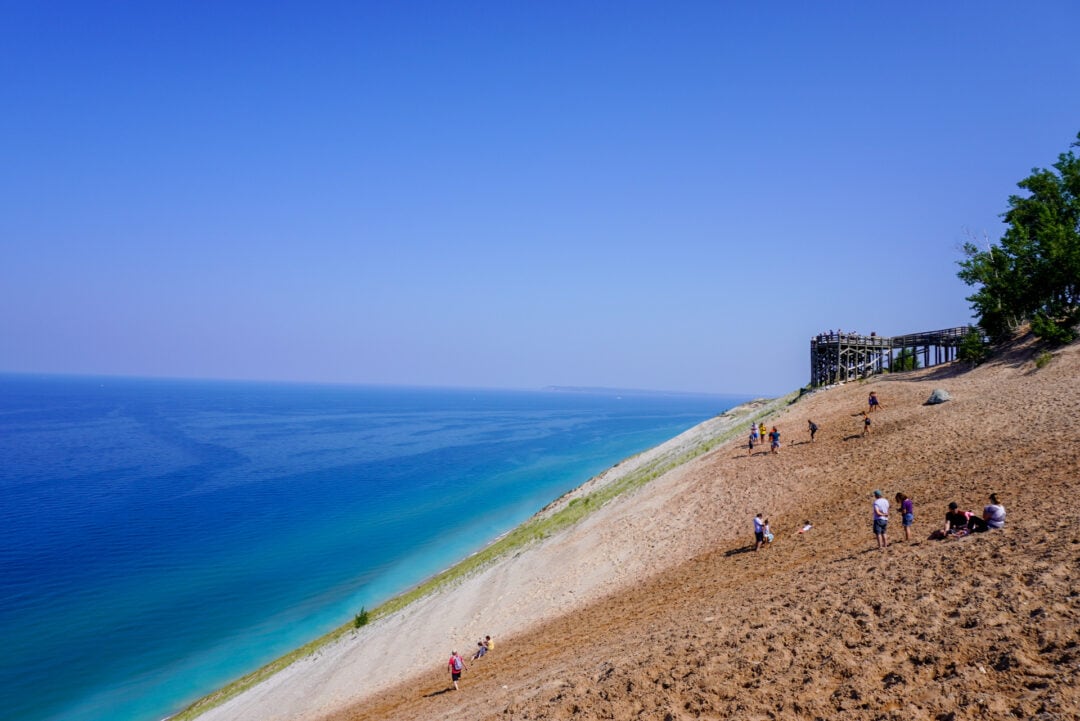 A steep, sandy slope leads into a blue lake
